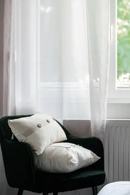 a chair with two pillows sitting in front of a window at Logis hôtel restaurant Auberge de l'Espinouse in Fraisse-sur-Agout