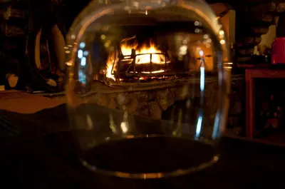 a glass sitting on a table in front of a fireplace at Logis hôtel restaurant Auberge de l'Espinouse in Fraisse-sur-Agout