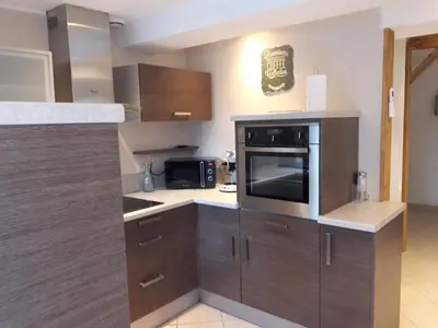 a kitchen with wooden cabinets and a microwave at La Coulée Douce - Chez Antoine in Castelnaudary