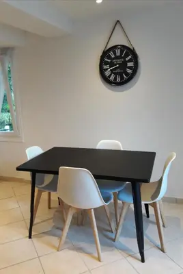a black table with chairs and a clock on a wall at La Coulée Douce - Chez Antoine in Castelnaudary