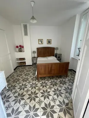 a bedroom with a bed and a tiled floor at Maison de la Fontaine in Embres-et-Castelmaure