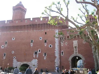 a large red brick building with a tower at Maison de la Fontaine in Embres-et-Castelmaure
