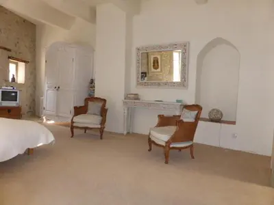 a bedroom with a bed and two chairs and a fireplace at Maison de caractère face à l abbaye de lagrasse in Lagrasse