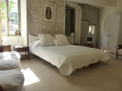 a bedroom with a large white bed and a couch at Maison de caractère face à l abbaye de lagrasse in Lagrasse