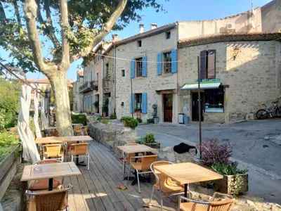 a group of tables and chairs in front of a building at Maison de caractère face à l abbaye de lagrasse in Lagrasse