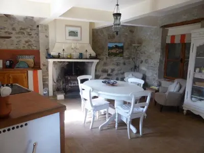 a kitchen and living room with a table and chairs at Maison de caractère face à l abbaye de lagrasse in Lagrasse