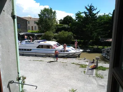 a group of people standing next to a boat at La maison de l'écluse in Trèbes