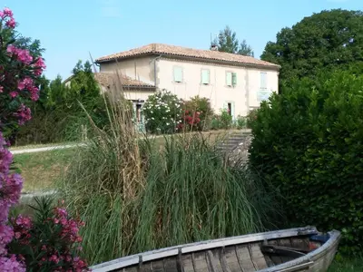 a house and a wooden boat in front of a yard at La maison de l'écluse in Trèbes