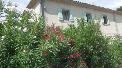 a house with pink flowers in front of a building at La maison de l'écluse in Trèbes
