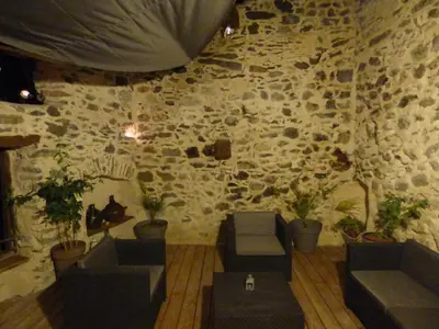 a room with a stone wall with couches and plants at L'Ostalet in Prugnanes