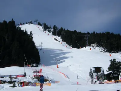a snow covered ski slope with orange flags on it at L'Ostalet in Prugnanes