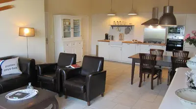 a living room with a table and chairs and a kitchen at Domaine de la Bade in Raissac-sur-Lampy