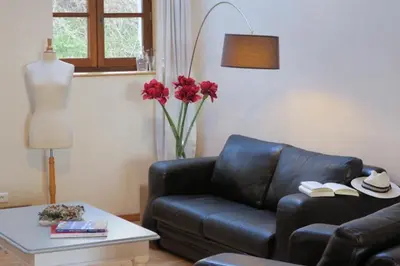 a living room with a black leather couch and a table at Domaine de la Bade in Raissac-sur-Lampy