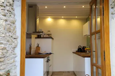 a kitchen with white walls and a stone wall at Domaine de la Bade in Raissac-sur-Lampy