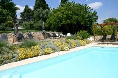 a swimming pool in a garden with chairs and flowers at Domaine de la Bade in Raissac-sur-Lampy