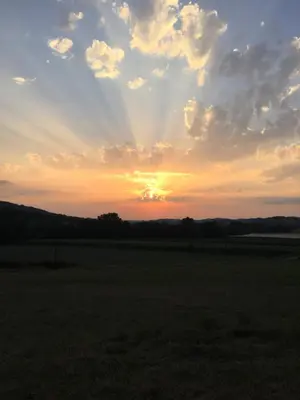 a sunset in a field with the sun in the sky at Chambres Ambroisie in Gueytes-et-Labastide