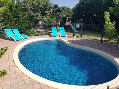 a swimming pool with blue chairs and a swing at Villa La Milouyette in Peyriac-Minervois