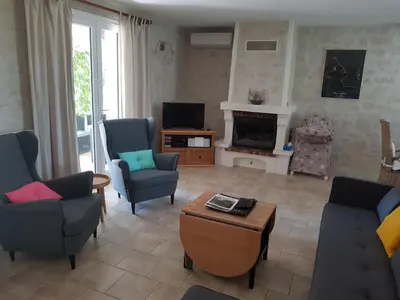 a living room with chairs and a tv and a table at Villa La Milouyette in Peyriac-Minervois