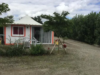 a small red and white house with a tree at Parc Des Oliviers in Gaudiès