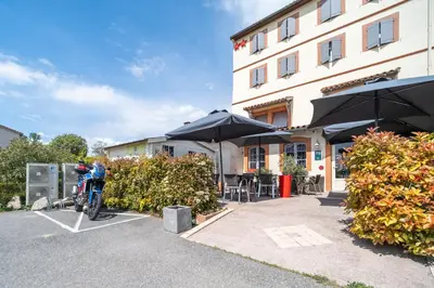 a motorcycle parked in a parking lot next to a building at Hôtel Restaurant du Lauragais LOGIS DE FRANCE in Villefranche-de-Lauragais