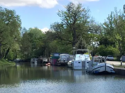 a group of boats are docked in a river at Hôtel Restaurant du Lauragais LOGIS DE FRANCE in Villefranche-de-Lauragais