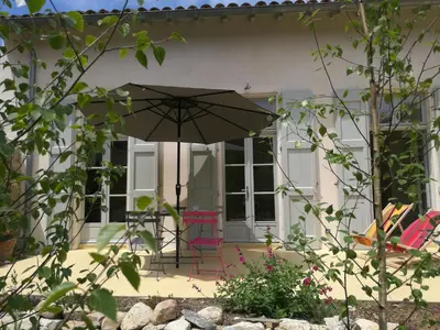 a patio with an umbrella and chairs in front of a house at Gîte Maison de l'Abbé in Sorèze