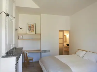 a white bedroom with a bed and a desk at Gîte Maison de l'Abbé in Sorèze