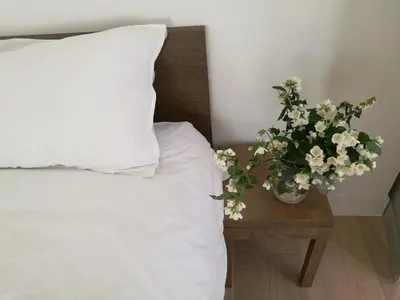 a bed with a pillow and a vase of flowers on a table at Gîte Maison de l'Abbé in Sorèze
