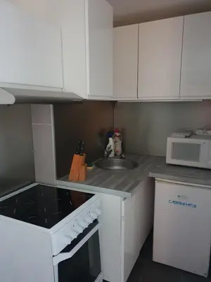 a small kitchen with white cabinets and a sink at logis 194 in Gruissan