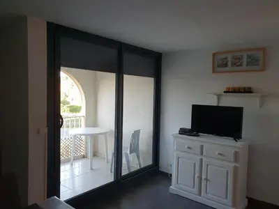 a living room with a sliding glass door with a television at logis 194 in Gruissan