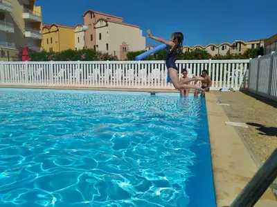 a girl jumping into a swimming pool with a frisbee at logis 149 in Gruissan