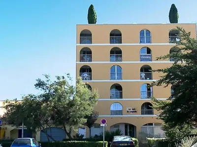 a large building with cars parked in front of it at logis 149 in Gruissan