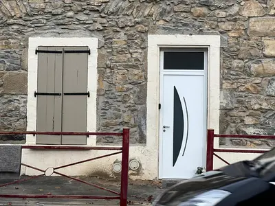a stone building with a white door and windows at maison des corbieres in Conilhac-Corbières