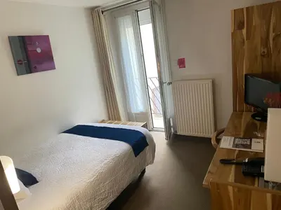 a bedroom with a bed and a television and a window at Logis Hôtel de France & Restaurant Pamiers in Pamiers