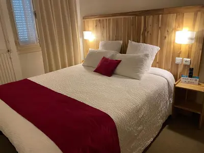 a bedroom with a large bed with red and white pillows at Logis Hôtel de France & Restaurant Pamiers in Pamiers