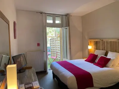 a bedroom with a large bed with red pillows at Logis Hôtel de France & Restaurant Pamiers in Pamiers