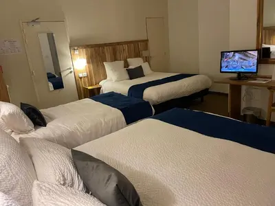 a hotel room with three beds and a flat screen tv at Logis Hôtel de France & Restaurant Pamiers in Pamiers
