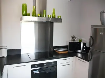 a kitchen with a black counter top and a refrigerator at Appartement Le Saint Nazaire - Les Balcons de la Cité in Carcassonne