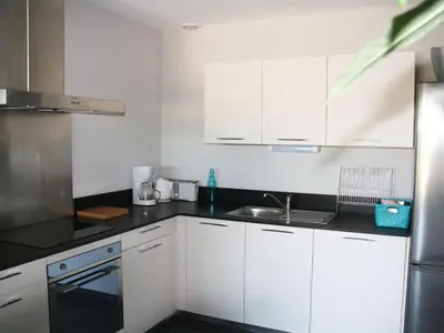 a kitchen with white cabinets and a sink at Appartement Le Saint Nazaire - Les Balcons de la Cité in Carcassonne