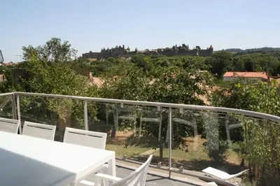 a balcony with a white table and chairs and trees at Appartement Le Saint Nazaire - Les Balcons de la Cité in Carcassonne
