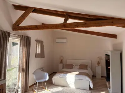 a bedroom with a white bed and a white chair at L'Ecurie en ville in Limoux