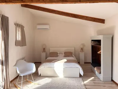 a bedroom with a white bed and a white chair at L'Ecurie en ville in Limoux