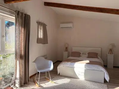 a bedroom with a bed and a chair and a window at L'Ecurie en ville in Limoux