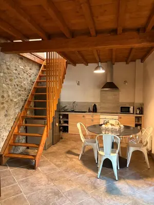 a kitchen with a wooden staircase and a table and chairs at L'Ecurie en ville in Limoux