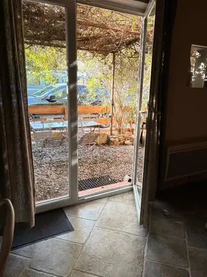 an open door to a patio with a view of a park at L'Ecurie en ville in Limoux
