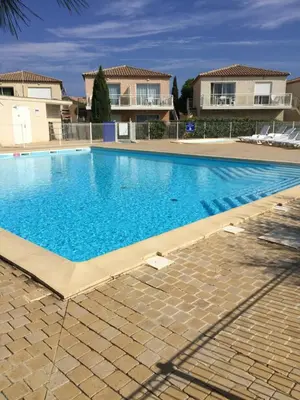 a large blue swimming pool in front of some houses at Résidence les jardins du phoebus appartement in Gruissan