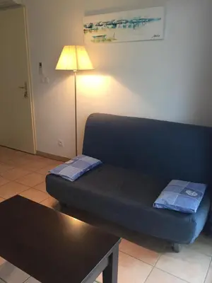 a couch in a living room with a table and a lamp at Résidence les jardins du phoebus appartement in Gruissan