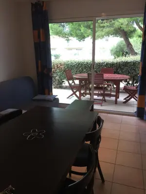 a dining room with a table and chairs and a patio at Résidence les jardins du phoebus appartement in Gruissan