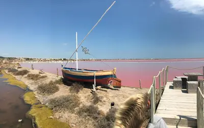 a boat sitting on the shore of a body of water at Résidence les jardins du phoebus appartement in Gruissan