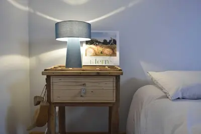 a nightstand with a lamp on it next to a bed at Appartement d'Hôtes Temps de Pause in Lautrec